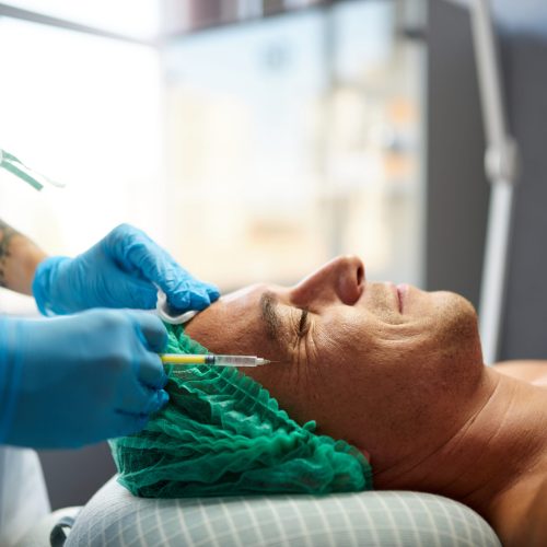 Anti-aging procedures in cosmetological cabinet, smiling client, side view